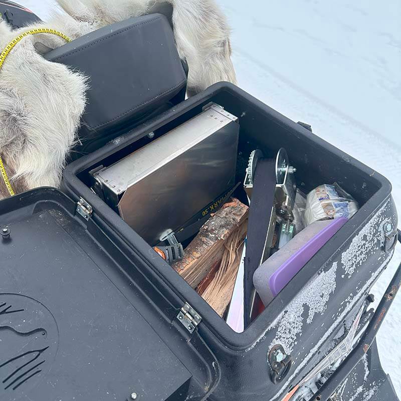 Öppen packlåda bak på en snöskoter Lynx Commander. I lådan finns Sorselelyft, Eldbox och ved.