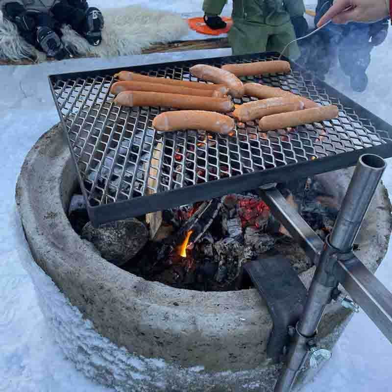 Grillgaller med cementfäste är monterat på en cementring. På gallret ligger korvar för grillning.